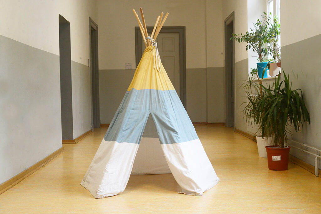 Ein Tipi-Zelt und Pflanzen in einem hellen Schulflur.