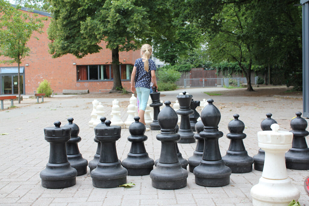 Großes Schachspiel mit kniehohen Figuren auf dem Schulhof.