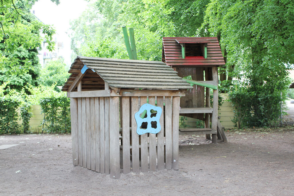 Holzspielhaus mit Kletterturm auf dem Schulhof.