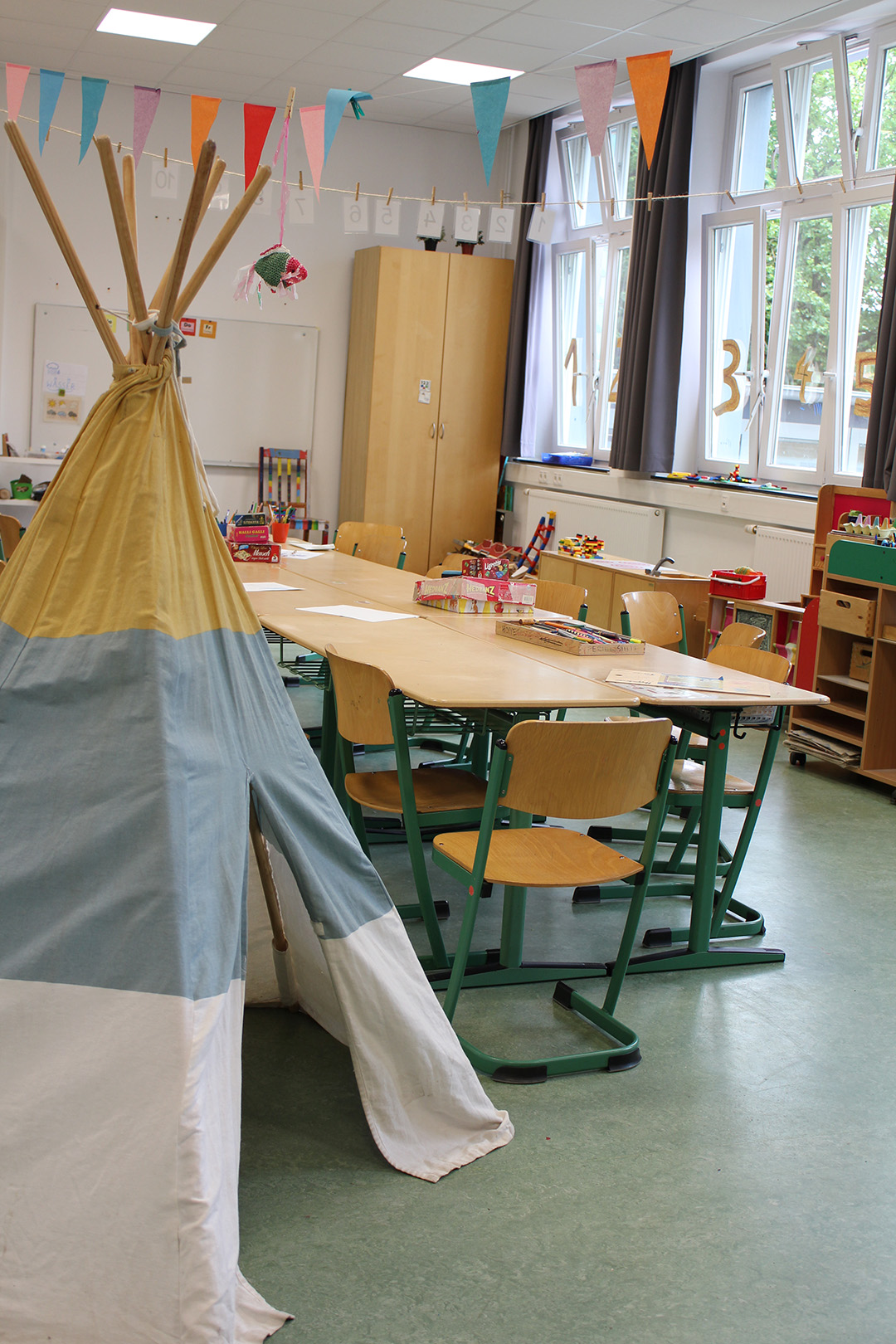 Klassenraum mit Tischgruppen, Wimpelkette und einem Tipi-Zelt.