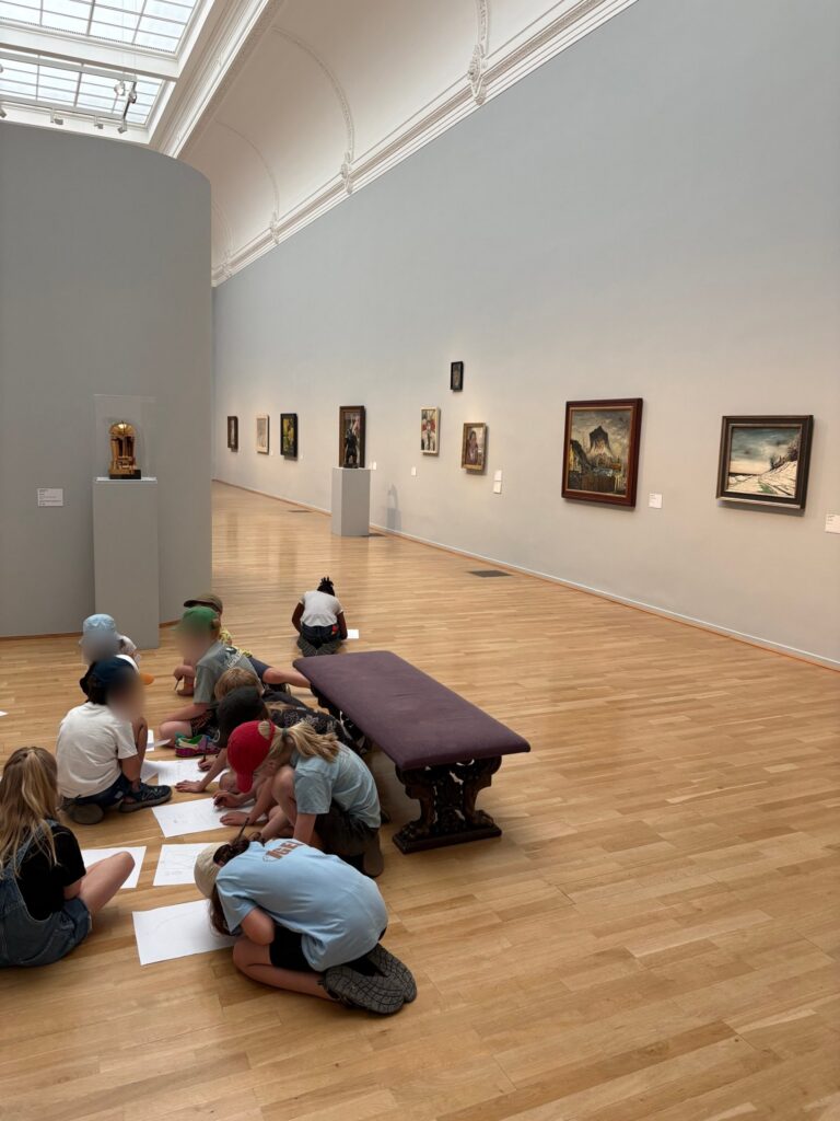 Eine Gruppe Kinder zeichnet in einer langen Ausstellungshalle der Kunsthalle