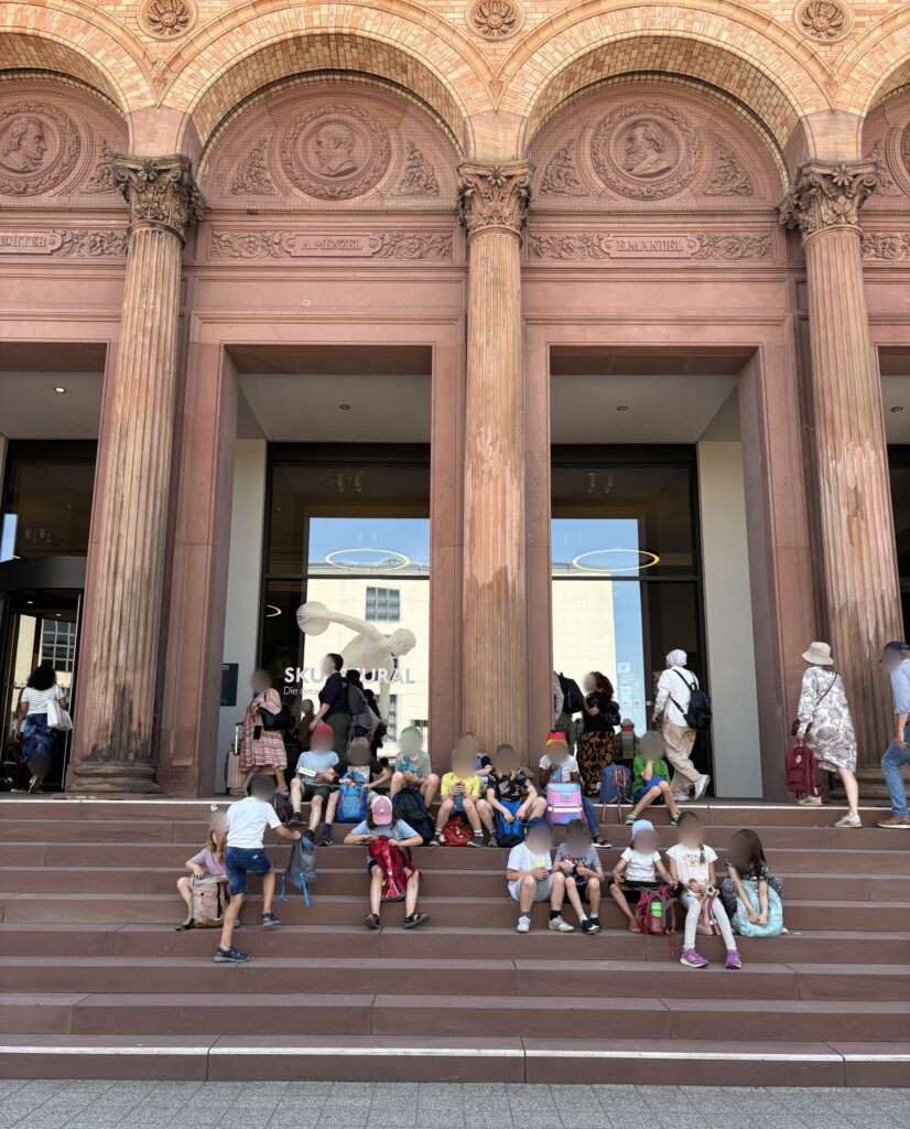 Die Kinder machen Pause auf den Stufen vor dem Eingang der Kunsthalle