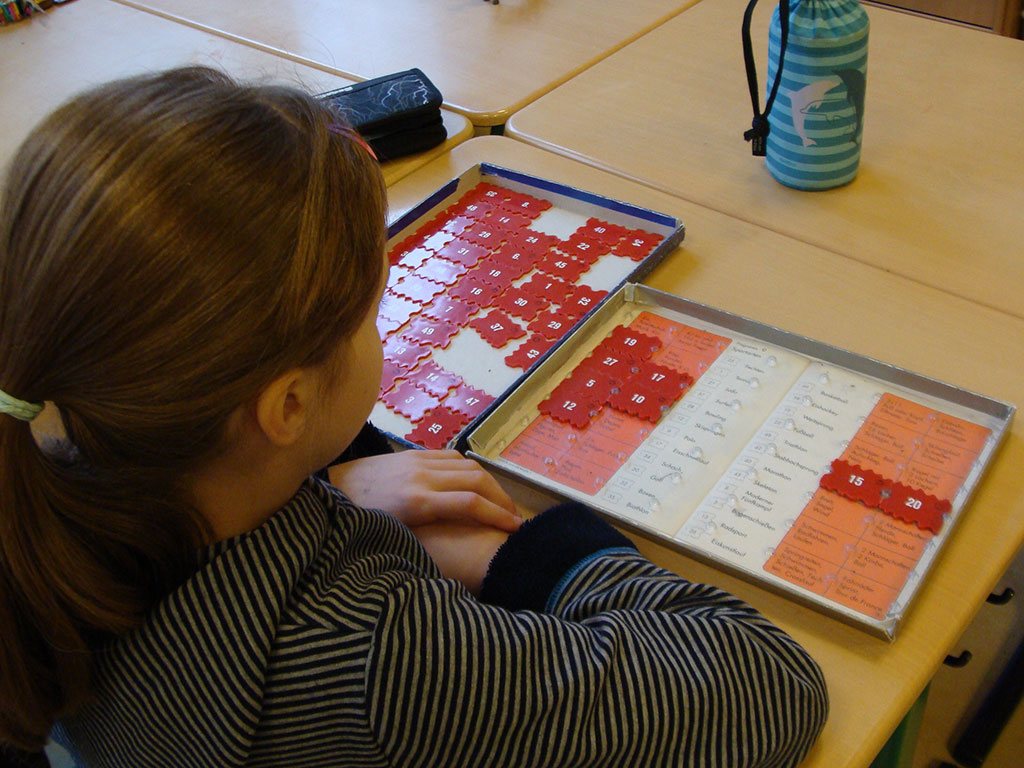 Ein Kind arbeitet mit Lernmaterial auf zwei Tabletts.