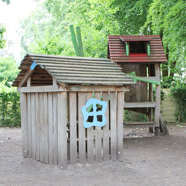 Holzspielhaus mit Kletterturm auf dem Schulhof.