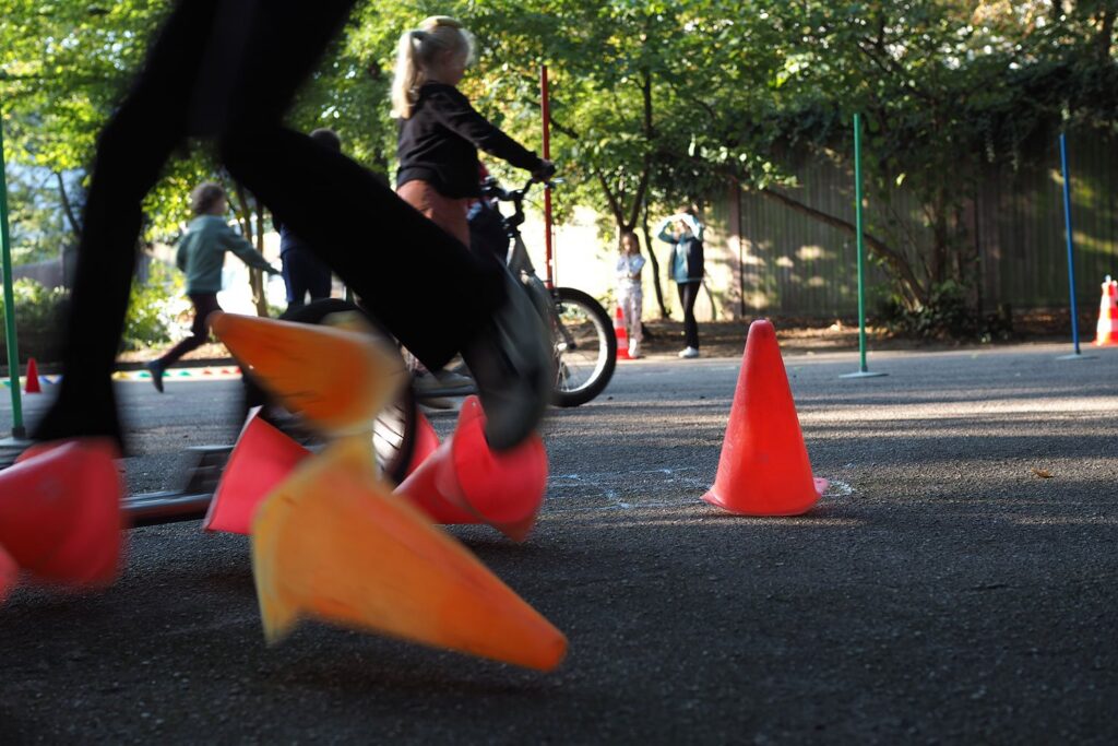 Kinder fahren mit dem Fahrrad einen Parcours mit Pylonen.