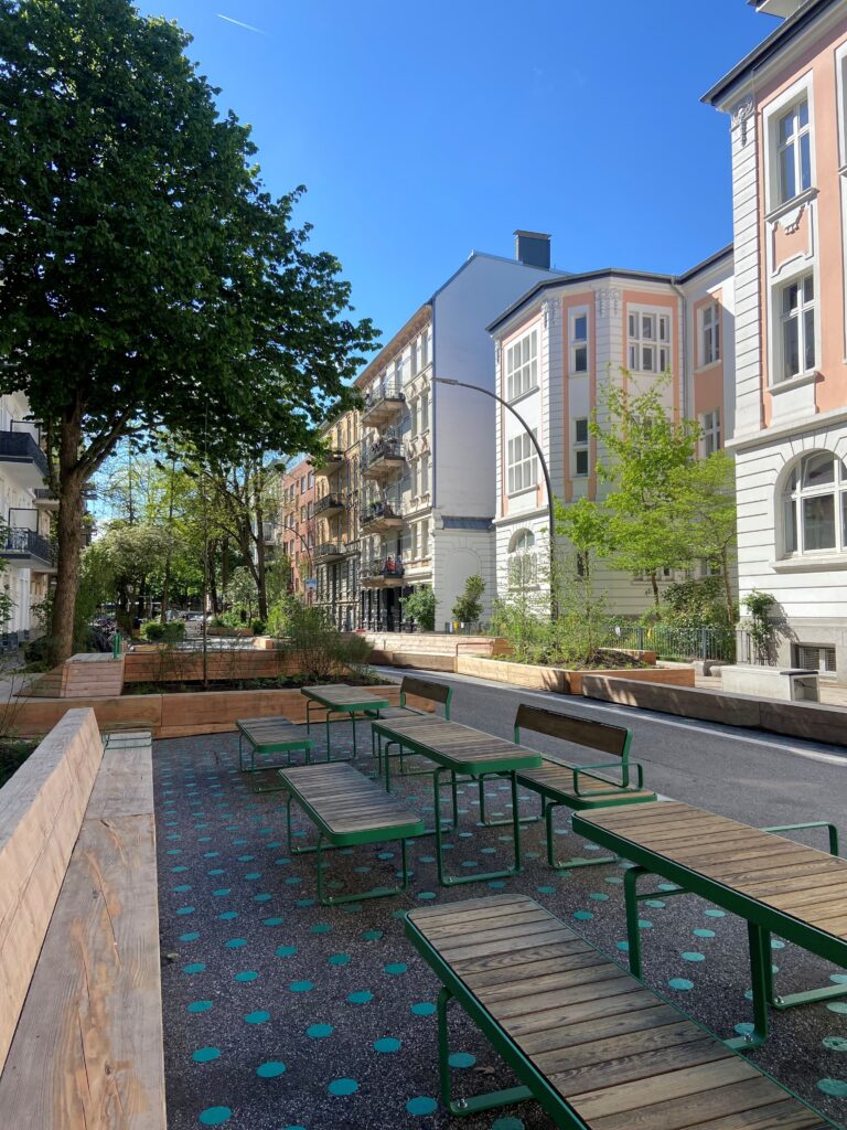 Die neu gestaltete Spielstraße vor der Schule mit Holzbänken und Tischen.