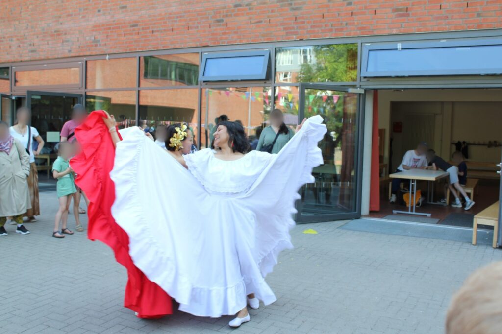 Tänzerinnen in weiten roten und weißen Röcken bei der Cumbia-Aufführung.