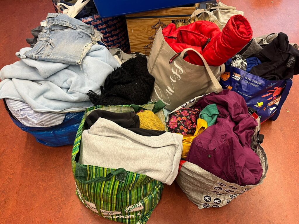 Berg aus gespendeter Kleidung in Taschen und Tüten