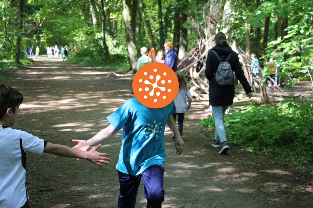 Zwei Kinder klatschen sich beim Waldlauf im Wald ab.