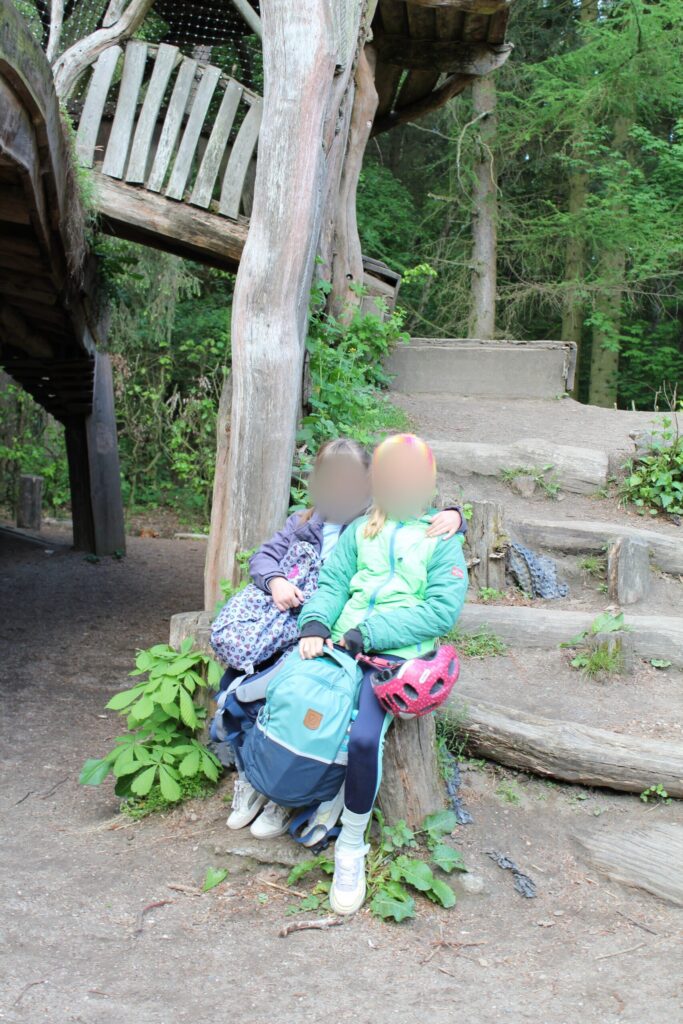 Kinder machen Pause an einer Holztreppe im Wald.