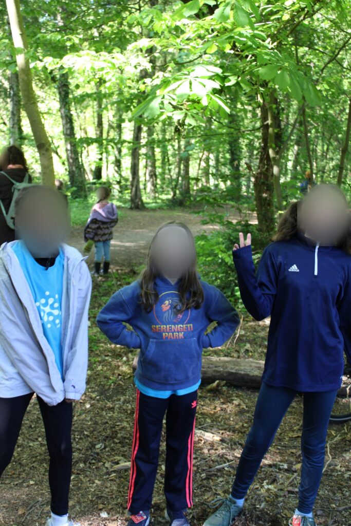 Drei Kinder stehen beim Waldlauf auf einem Waldweg.