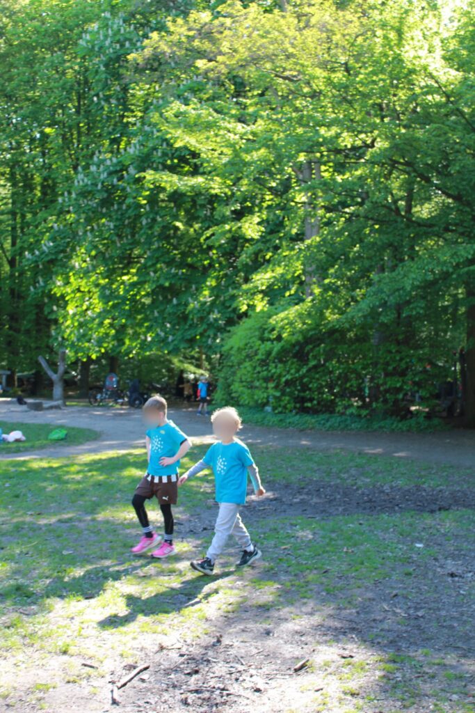 Zwei Kinder laufen über eine Lichtung im Wald.